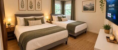A hotel room with two beds, a TV, a desk, and a window with curtains.