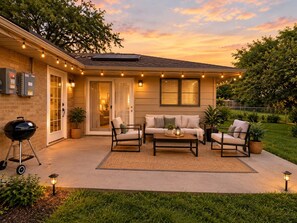 A residential property with a patio area featuring outdoor furniture, a barbecue grill, and ambient lighting. - Spacious Rockford Home | 4BR • 7 Beds • 4.5BA (Rockford)