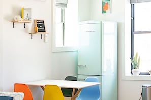 A room with a white table, colorful chairs, a light green refrigerator, and a window with a plant. - The Roosevelt: Upscale Loft blocks from downtown (Sioux Falls)