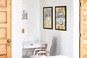A room with a white desk, a white chair, and two framed artworks on the wall. - The Roosevelt: Upscale Loft blocks from downtown (Sioux Falls)