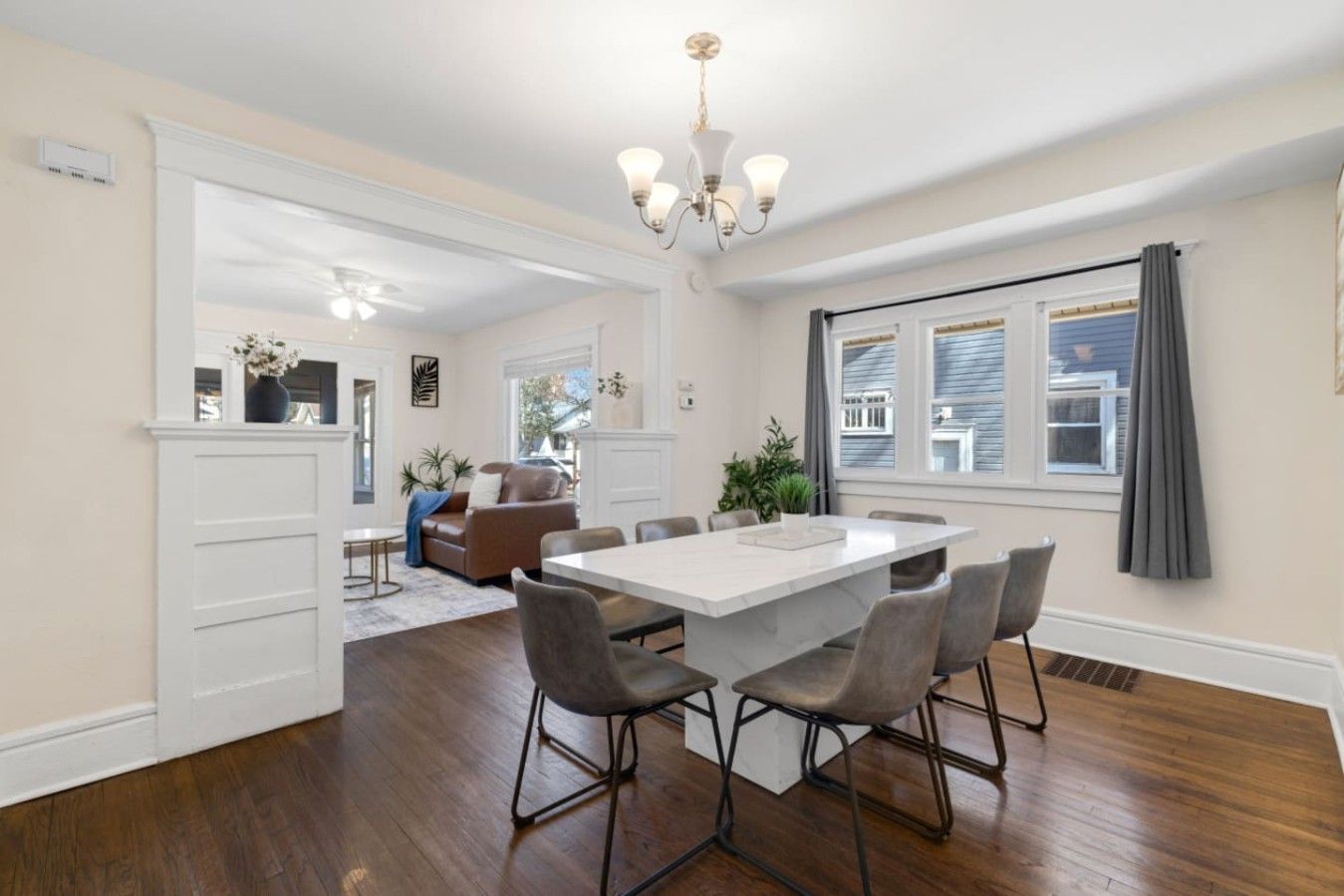 A modern kitchen with a central island, white cabinetry, and a dining area with a white table and grey chairs.