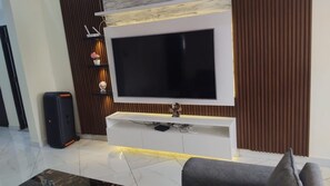 A modern living room with a large flat-screen TV mounted on a white entertainment unit. - A Perfect Home for the Family 3 Bed , (Accra Hills)