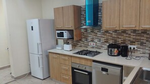 A compact kitchen with a refrigerator, microwave, toaster, gas stove, oven, and dishwasher. - A Perfect Home for the Family 3 Bed , (Accra Hills)