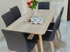 Una mesa de comedor con un jarrón de flores, una caja y cuatro sillas.