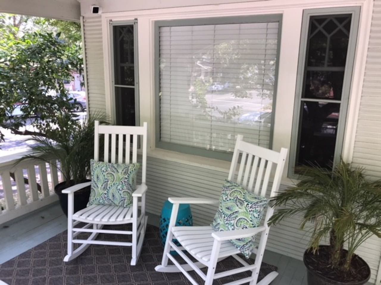 Een veranda met twee schommelstoelen en een potplant.