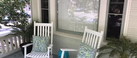 Een veranda met twee schommelstoelen en een potplant.
