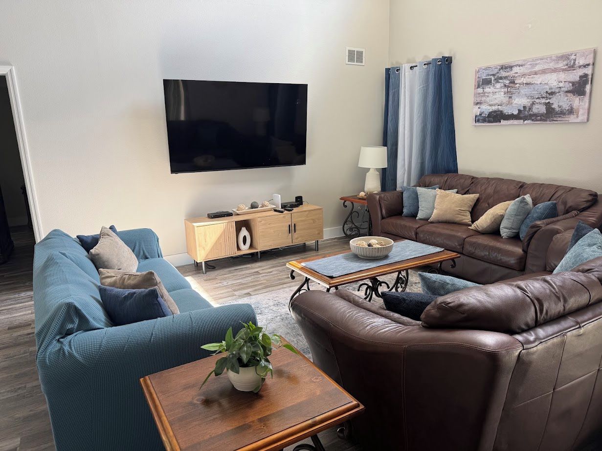 Un salon moderne avec un téléviseur à écran plat, deux canapés, une table basse et un buffet.