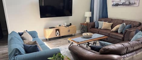A modern living room with a flat-screen TV, two sofas, a coffee table, and a sideboard.