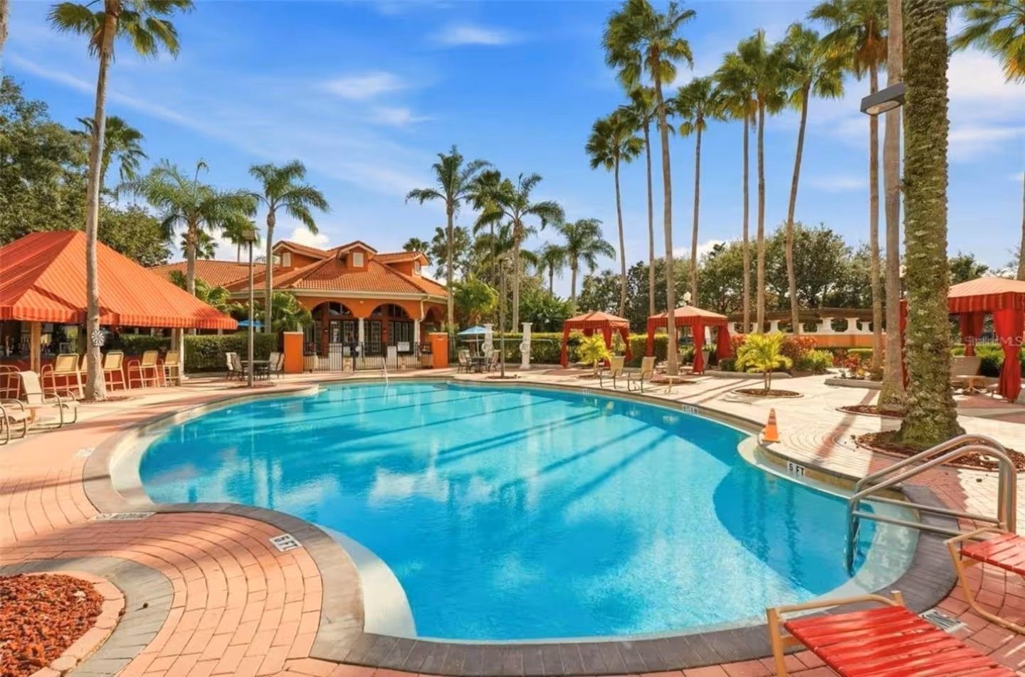 A swimming pool with lounge chairs and palm trees.