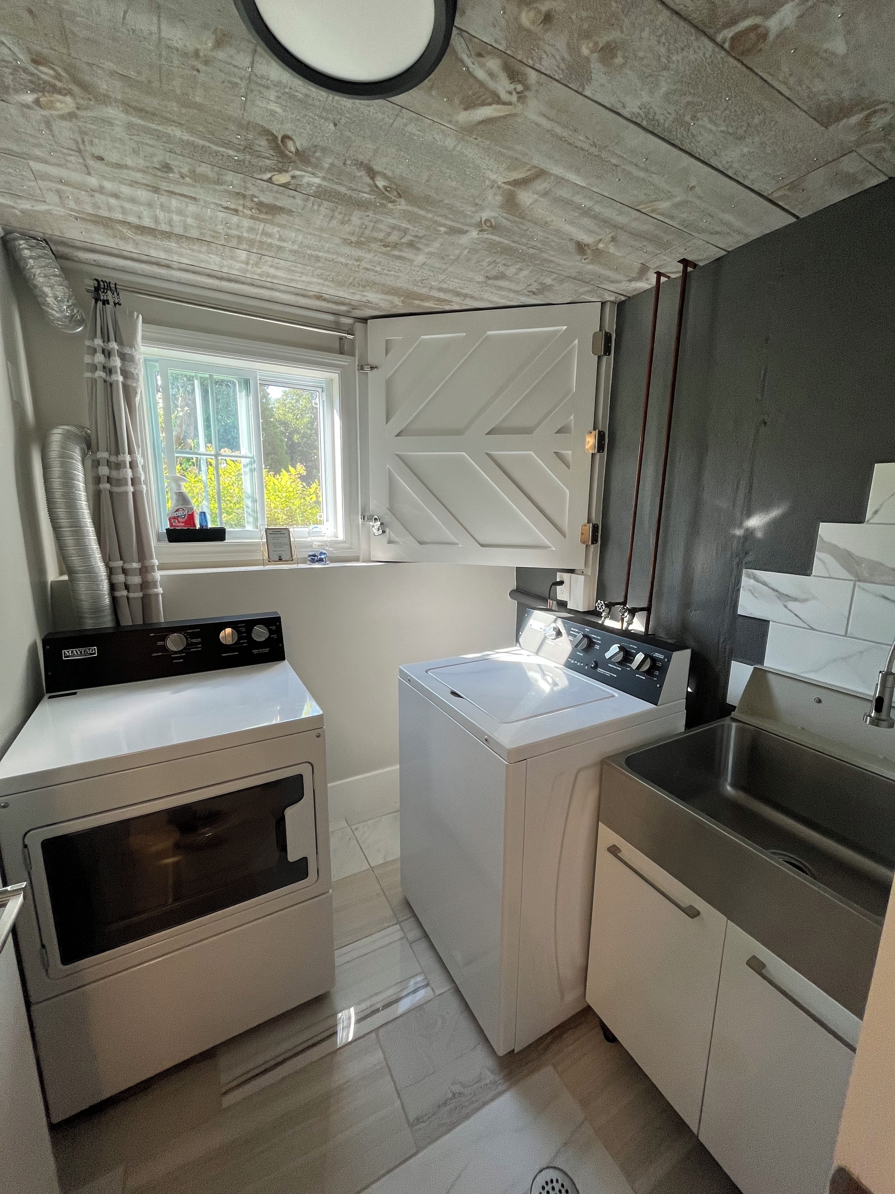 A compact laundry room with a washing machine, dryer, and a sink.