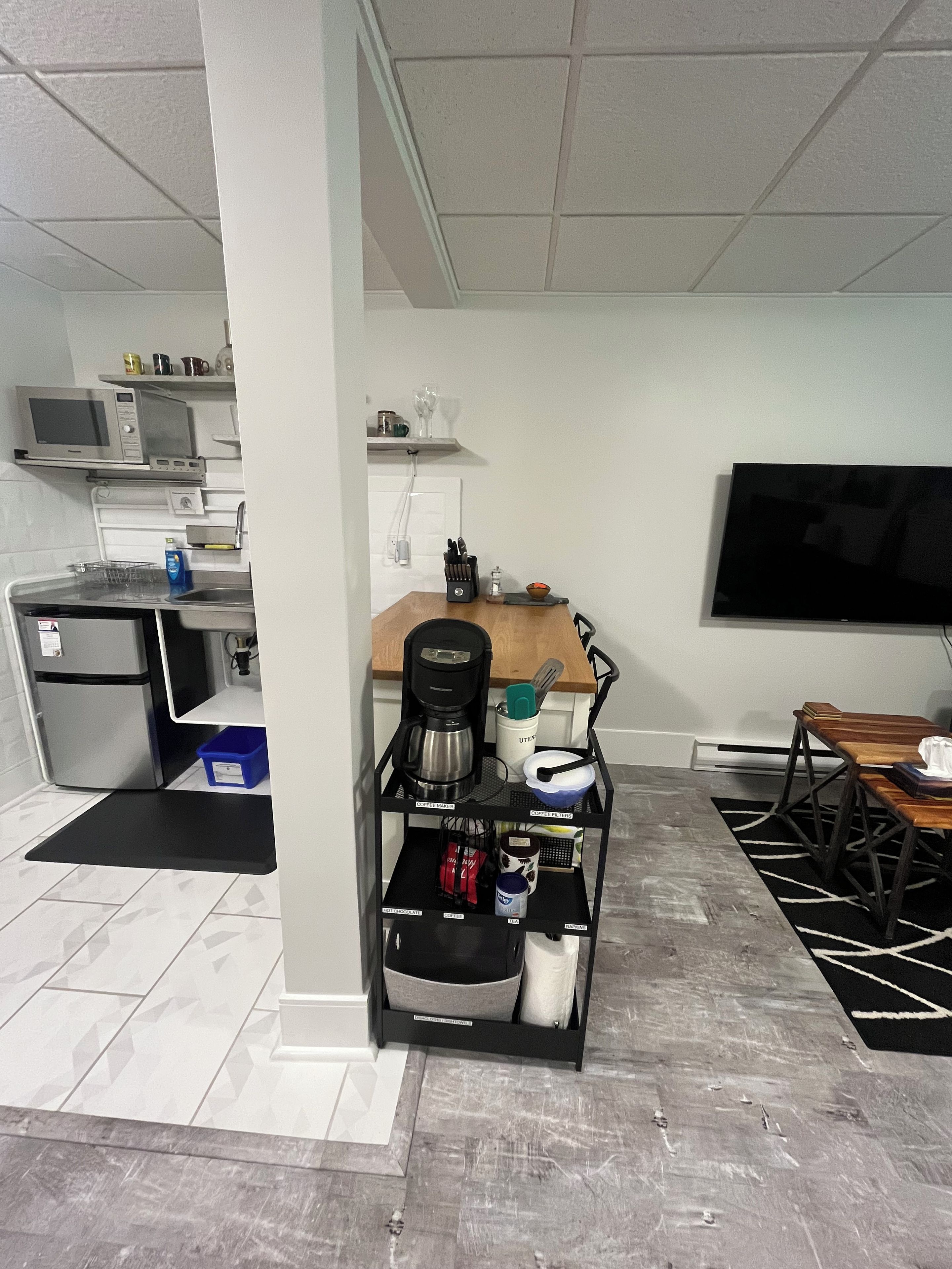 A compact living space with a kitchenette, a coffee machine, a TV, and a dining area.