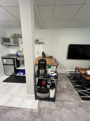 A compact living space with a kitchenette, a coffee machine, a TV, and a dining area.