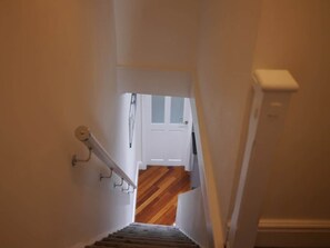 A narrow stairway leading to a room with a wooden floor and a white door. - Didsbury Village Apartment (Manchester)
