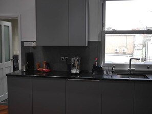 Een moderne keuken met een groot kookeiland, een inbouwoven en een raam met uitzicht op de stad.