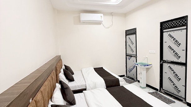 A hotel room with a long bed, a bedside table, an air conditioning unit, and decorative panels on the wall. - Hotel Vaishnavi Mahakal (UJJAIN)