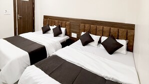 A hotel room with two beds, a wooden headboard, and a ceiling fan. - Hotel Vaishnavi Mahakal (UJJAIN)