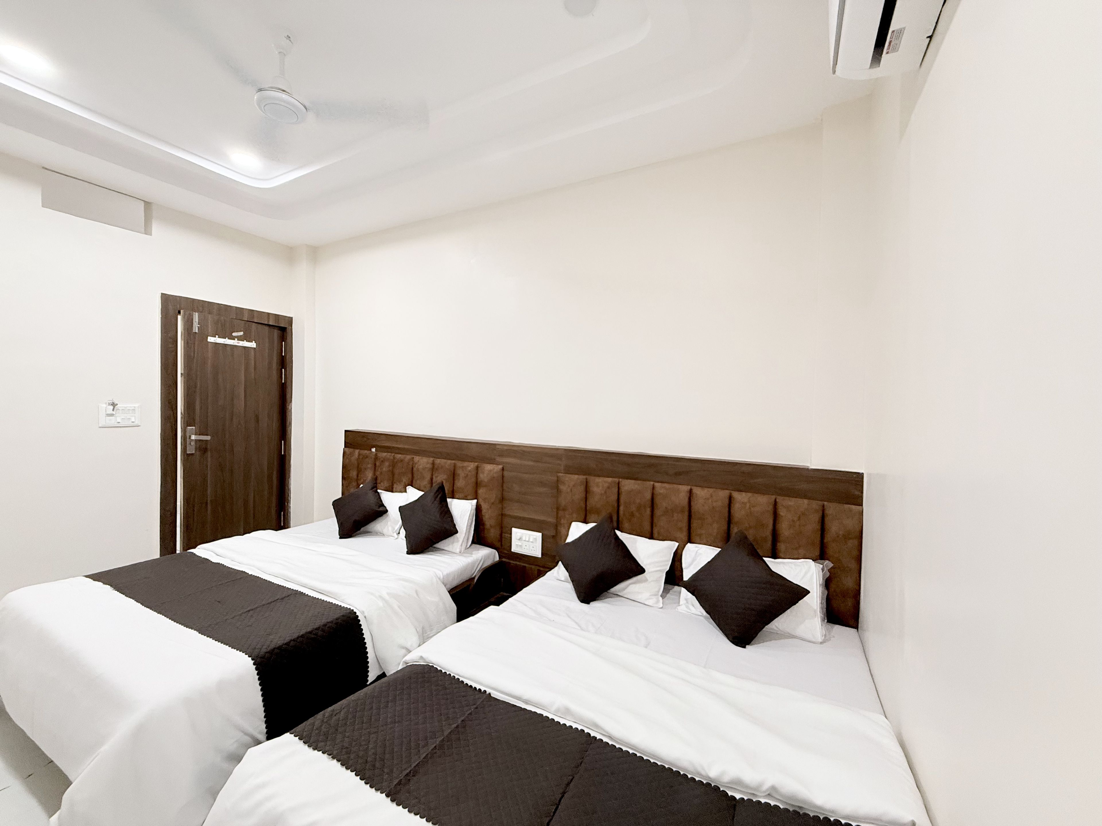 Habitación de hotel con dos camas, cabecero de madera y ventilador de techo.