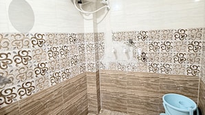 A bathroom with a shower, a toilet, and a hand dryer. - Hotel Vaishnavi Mahakal (UJJAIN)