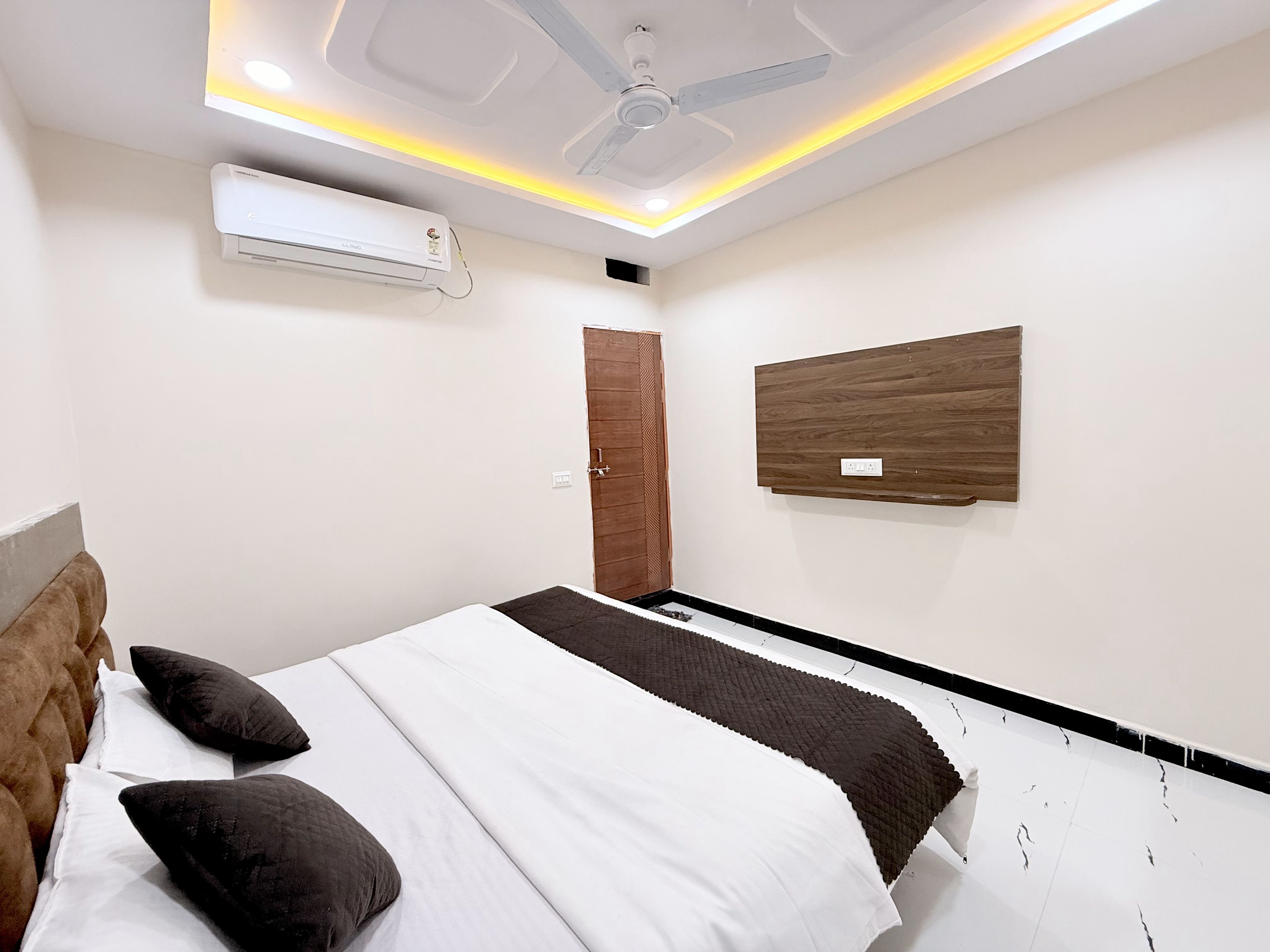 Un dormitorio con cama, ventilador de techo, aire acondicionado y un panel de madera en la pared.