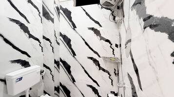 A bathroom with a marble wall, a shower, and a toilet.