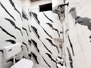 A bathroom with a marble wall, a shower, and a toilet. - Hotel Vaishnavi Mahakal (Ujjain)
