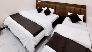 A hotel room with two beds, a ceiling fan, recessed lighting, and an air conditioning unit. - Hotel Vaishnavi Mahakal (UJJAIN)