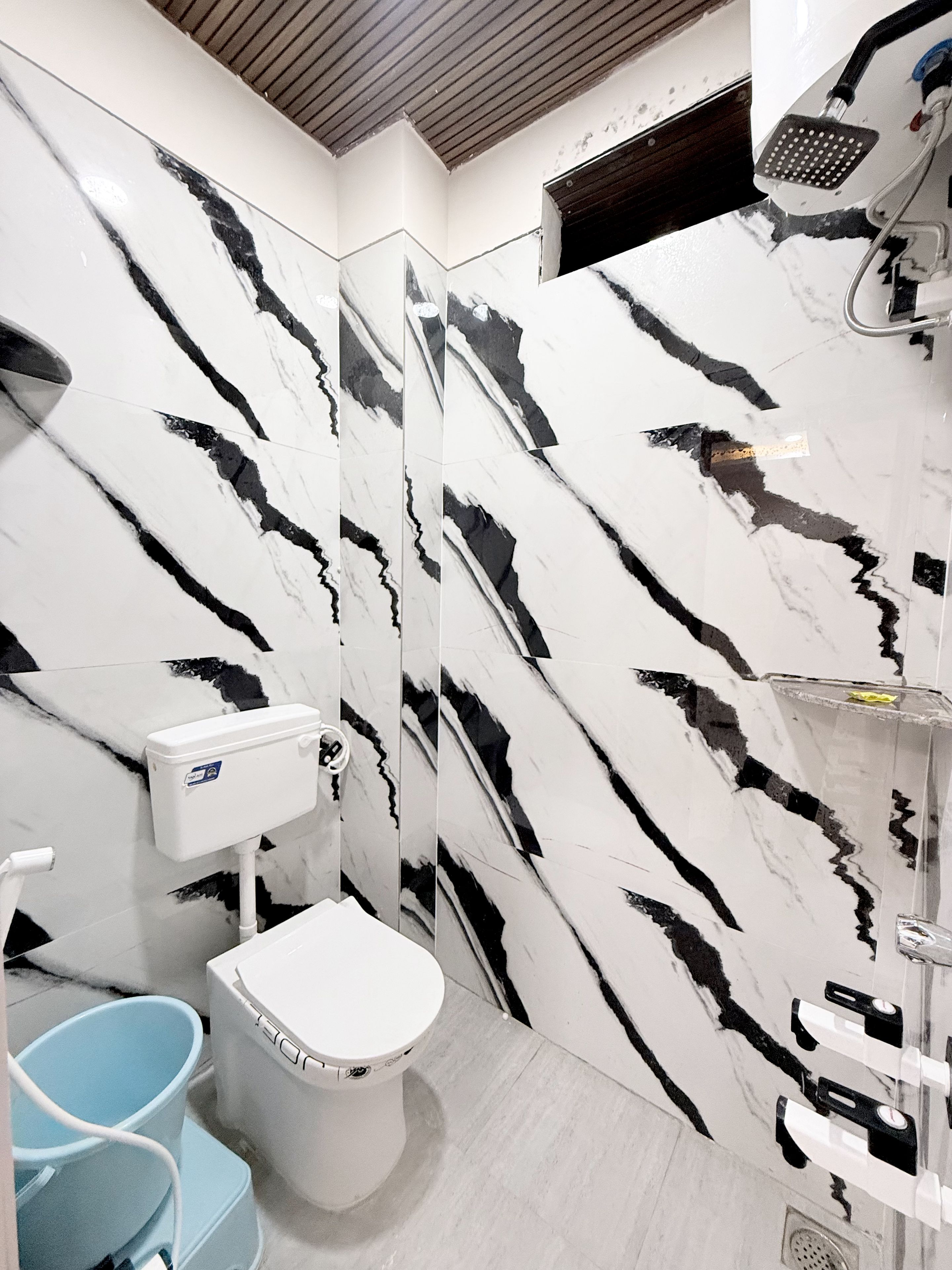 Un baño con inodoro, ducha y un cubo azul.