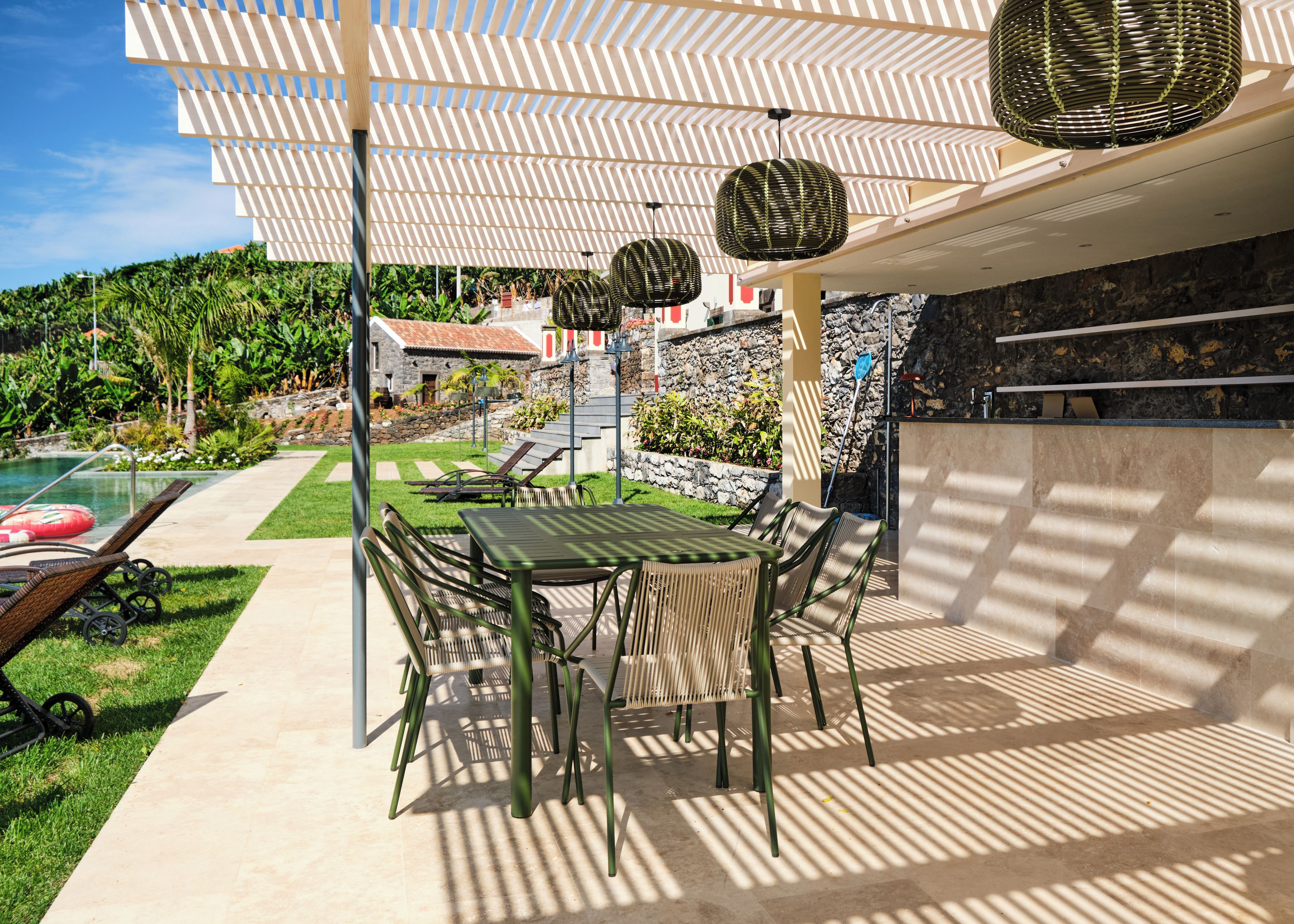 Un patio con tavolo e sedie, una piscina e un muro in pietra.