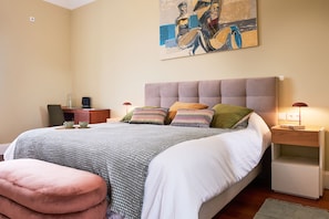 A bedroom with a bed, a nightstand, a lamp, and a painting on the wall.