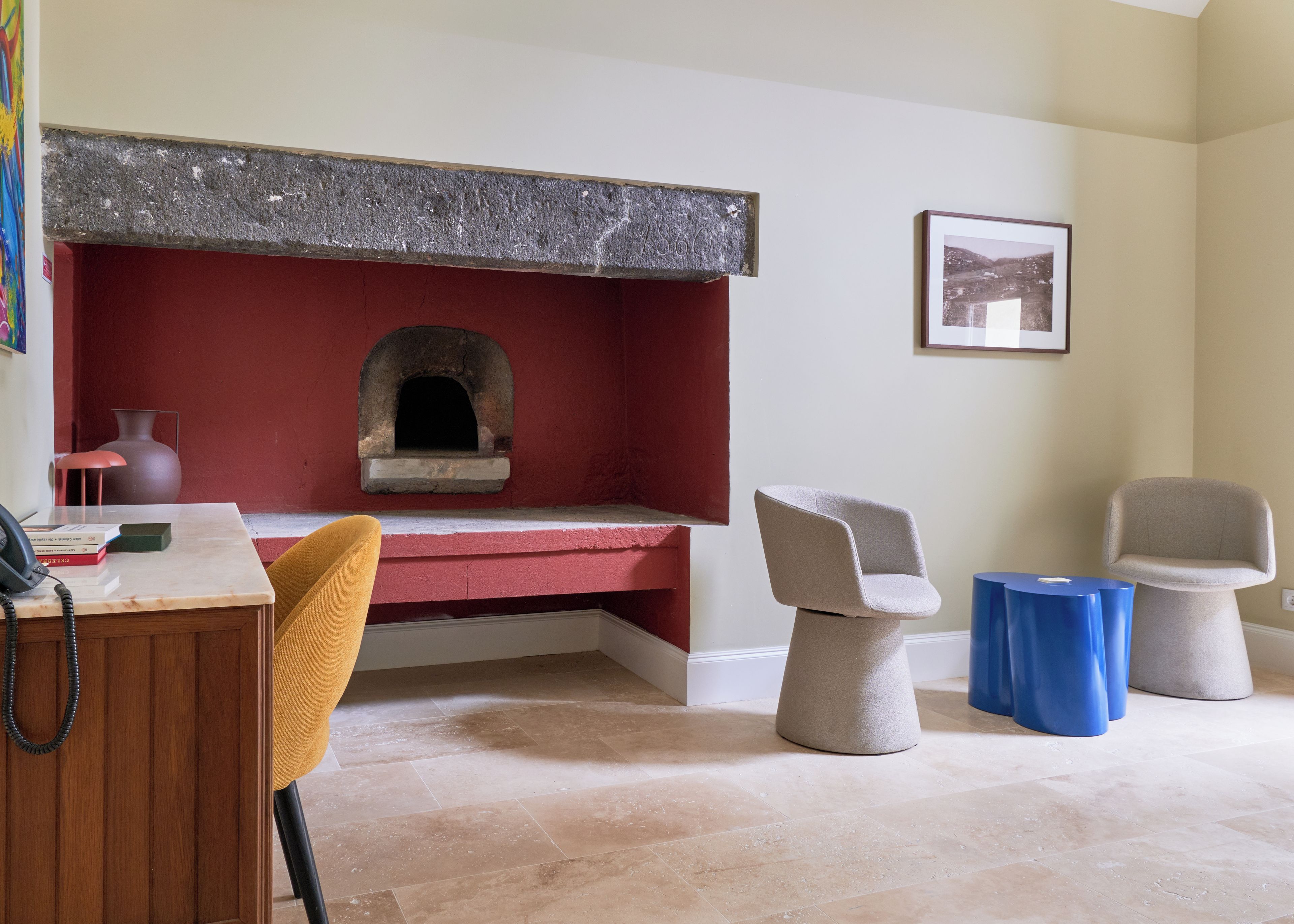 Ein Zimmer mit einem roten Kamin aus Ziegelsteinen, einem Holztisch mit Telefon und zwei modernen Stühlen.