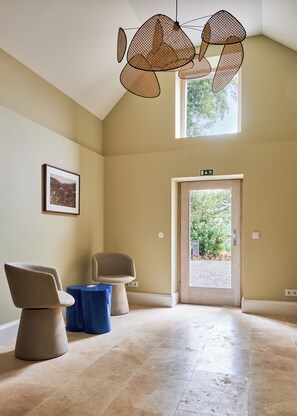 A spacious room with a high ceiling, a door leading outside, and two chairs. - Quinta do Serrado (Câmara de Lobos)