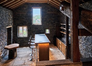 Una habitación rústica con paredes de piedra, una zona de bar, taburetes de madera y vistas a través de una ventana.