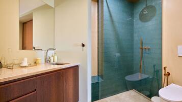 A bathroom with a glass-enclosed shower, a wooden vanity, and a white toilet.