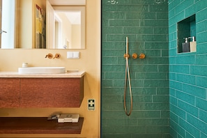 A bathroom with a white sink, a mirror, a green-tiled shower area, and a wooden vanity. - Quinta do Serrado (Câmara de Lobos)