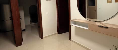 A room with a large mirror, a door, and a tiled floor.