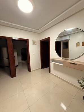 A room with a large mirror, a door, and a tiled floor.