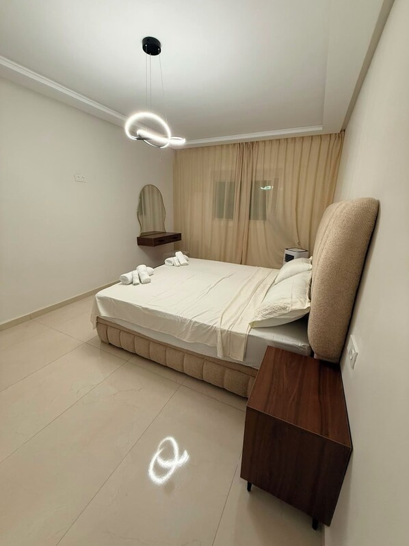 A modern bedroom with a bed, bedside table, and a ceiling light fixture.