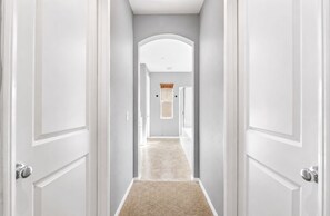 A hallway with white doors, a carpeted floor, and a light-colored wall. - 5BR Fallbrook Hideaway | Hot Tub + Scenic Getaways (Fallbrook)