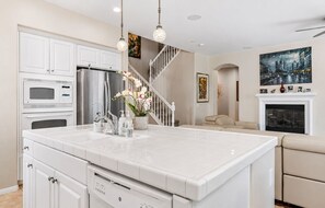 A modern kitchen with white cabinetry, a large island, stainless steel appliances, and pendant lighting. - 5BR Fallbrook Hideaway | Hot Tub + Scenic Getaways (Fallbrook)