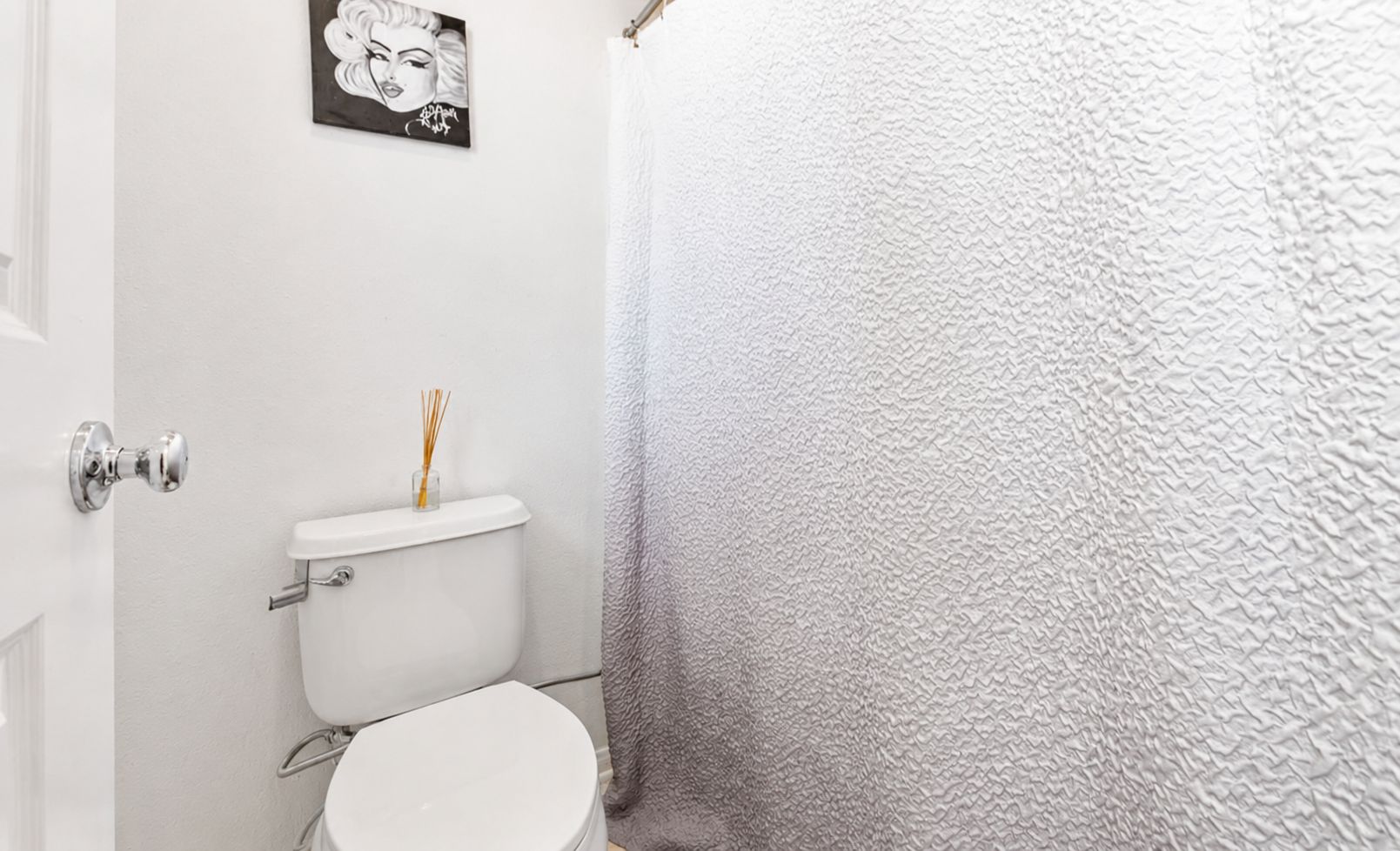 Une salle de bain avec des toilettes blanches, un porte-serviettes et un rideau de douche.