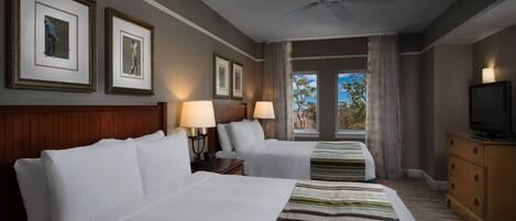 Habitación de hotel con dos camas, un televisor y cuadros en la pared.