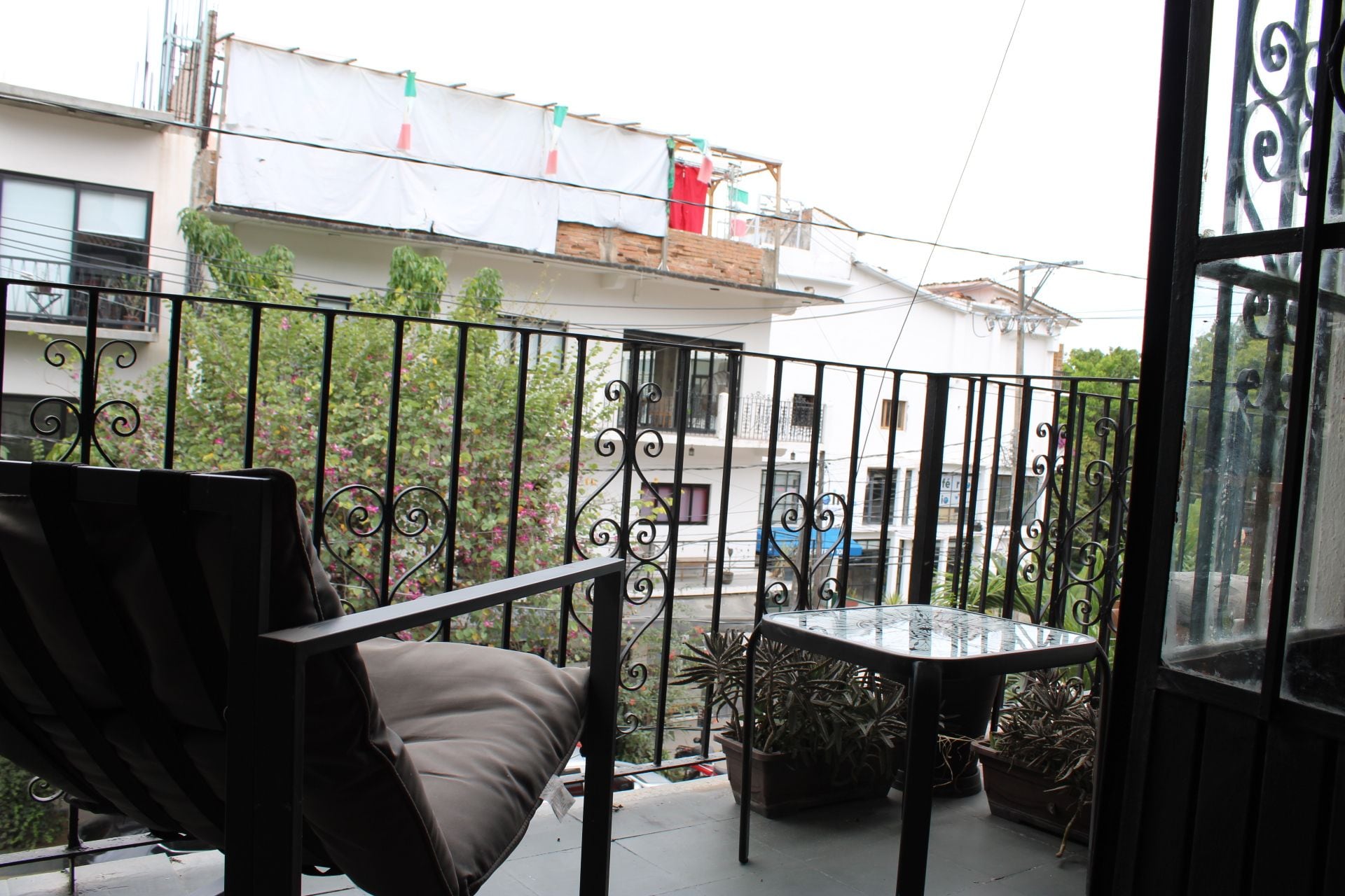 Un balcon agrémenté d’un canapé et d’une petite table, le tout entouré d’une balustrade en fer forgé.