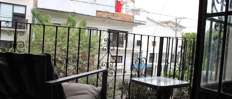 Un balcon agrémenté d’un canapé et d’une petite table, le tout entouré d’une balustrade en fer forgé.