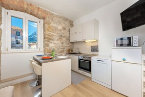 Eine kompakte Küche mit Steinwand, Backofen, Mikrowelle und Geschirrspüler.