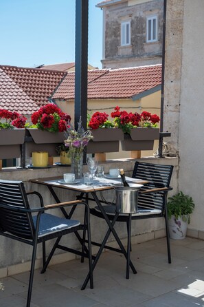 An outdoor patio with a table set for two, featuring a bottle of champagne, glasses, and a vase with flowers. - Lisko Old Town Apartment - Makarska (Makarska)