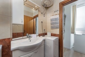 Een moderne badkamer met een ruime wastafel, spiegel en douche.