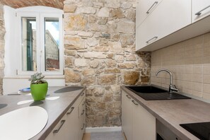 A kitchen with a stone wall, a window, and a sink. - Lisko Old Town Apartment - Makarska (Makarska)