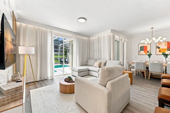 A modern living room with a sectional sofa, a coffee table, and a dining area with chairs and a table.