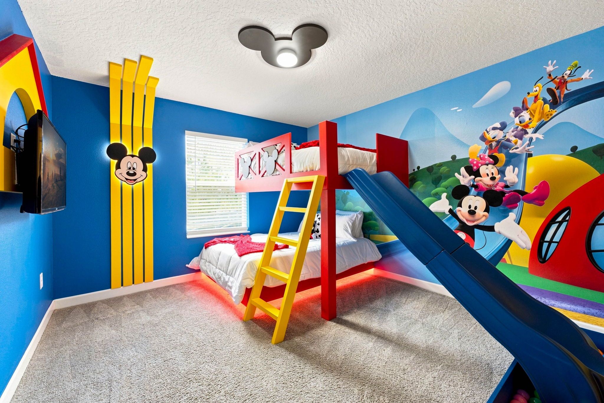 A child's room with a bunk bed, a Mickey Mouse wall decal, and a colorful mural.