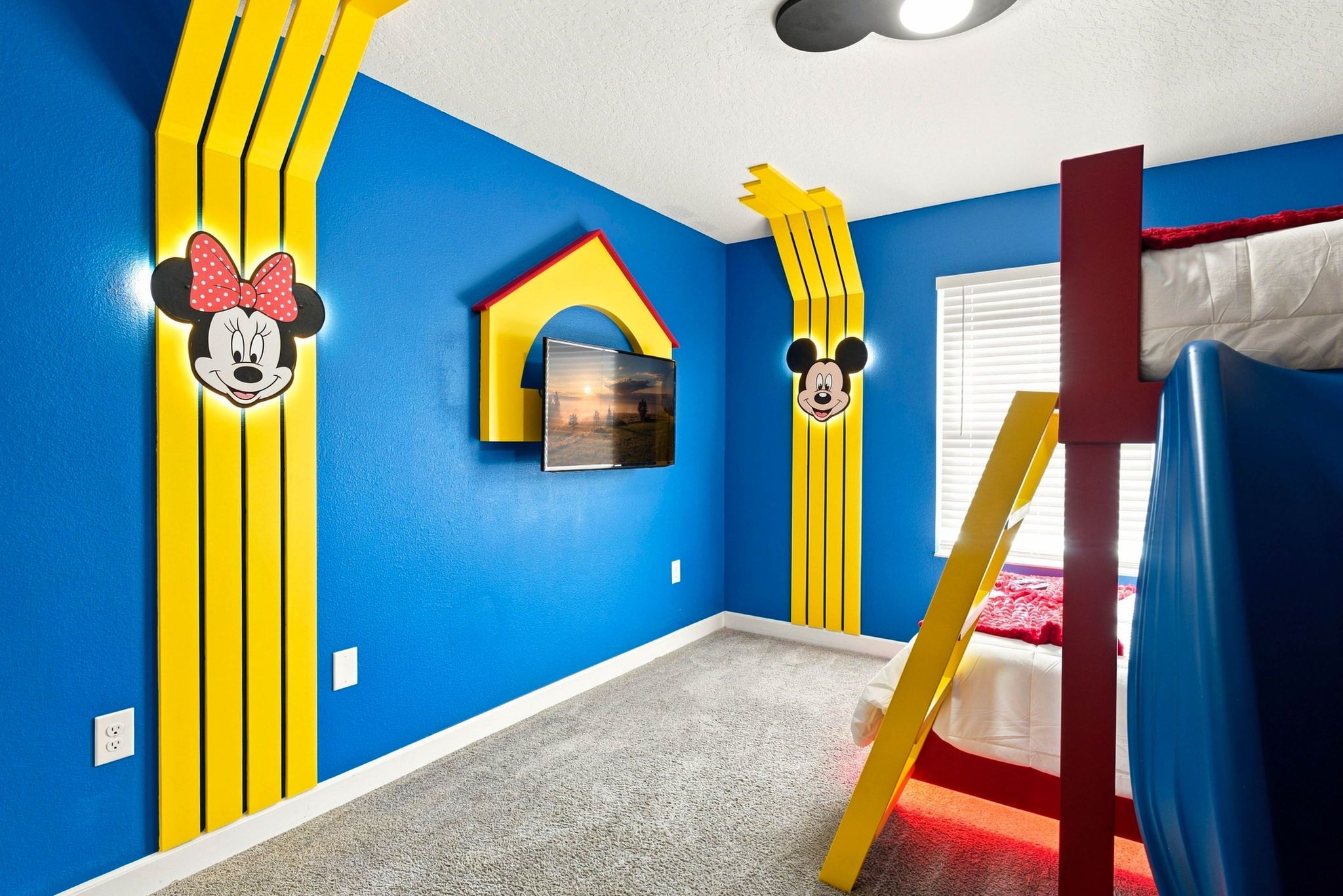 Een kamer met blauwe wanden, een stapelbed en Mickey Mouse decoraties.